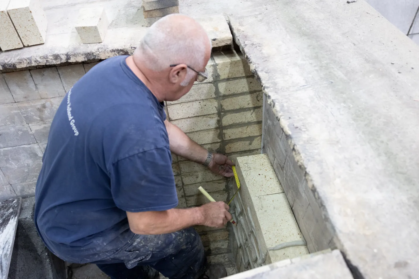 (meewerkend) voorman Ovenbouwer meet steen in